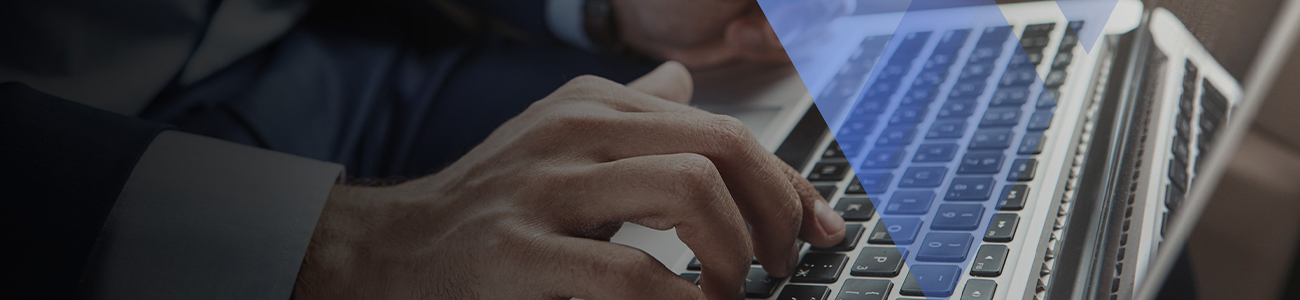 A close-up image of a person's hands typing on a laptop keyboard, with focus on the hands and the keyboard, set against a blurred background.